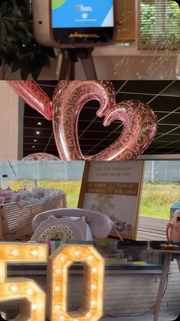 Lichtletters met het getal 50 en roze hartballonnen, met het scherm van de fotobooth erboven