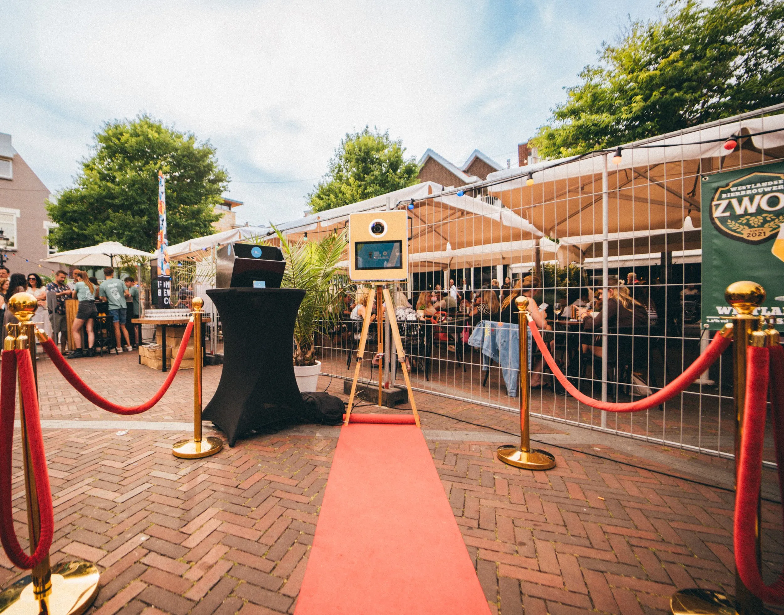 De photobooth op een rode loper met afzetpaaltjes tussen de terrassen op een plein