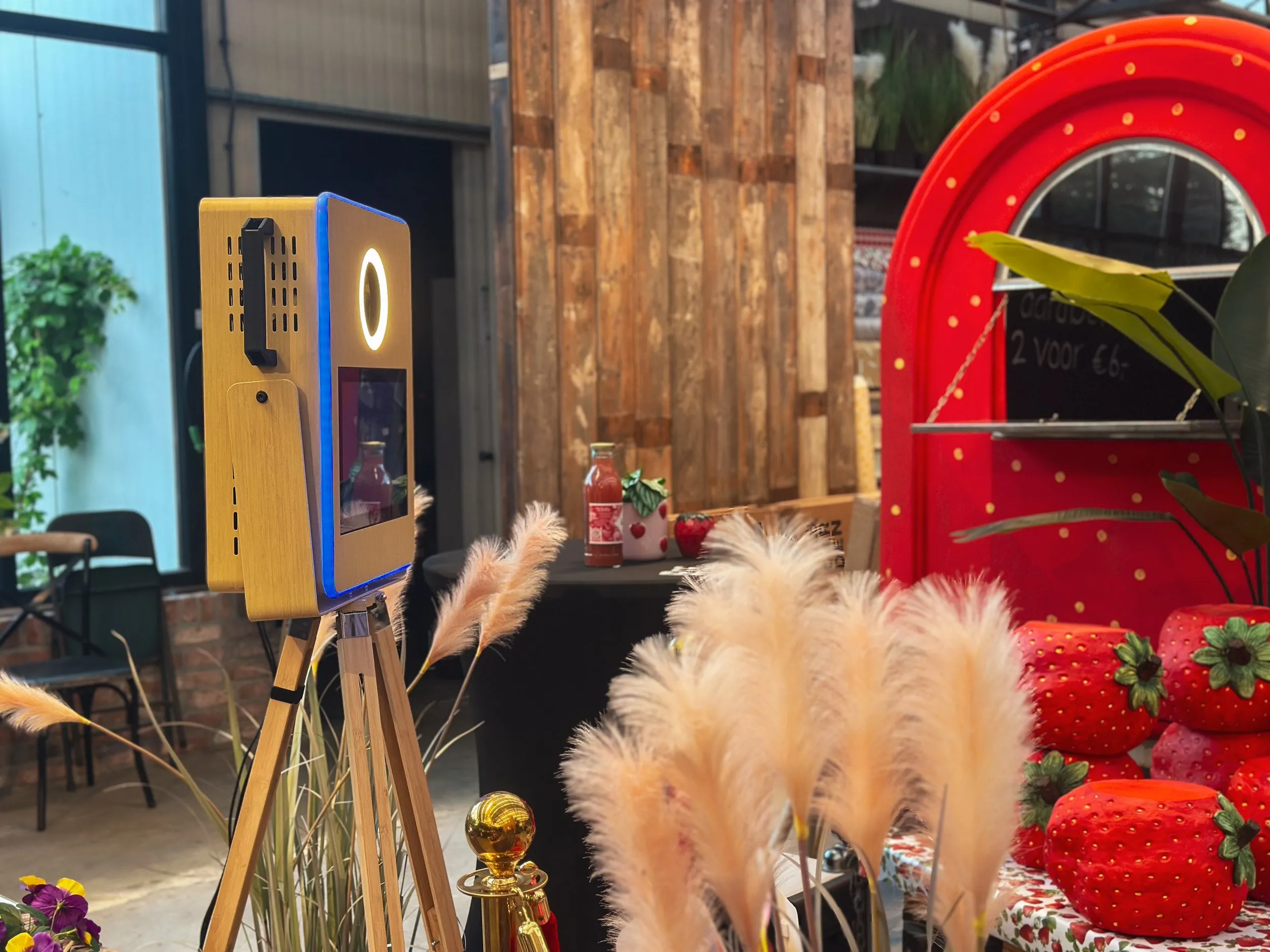 De photobooth op een houten statief tussen pampasgras en aardbeiendecoratie