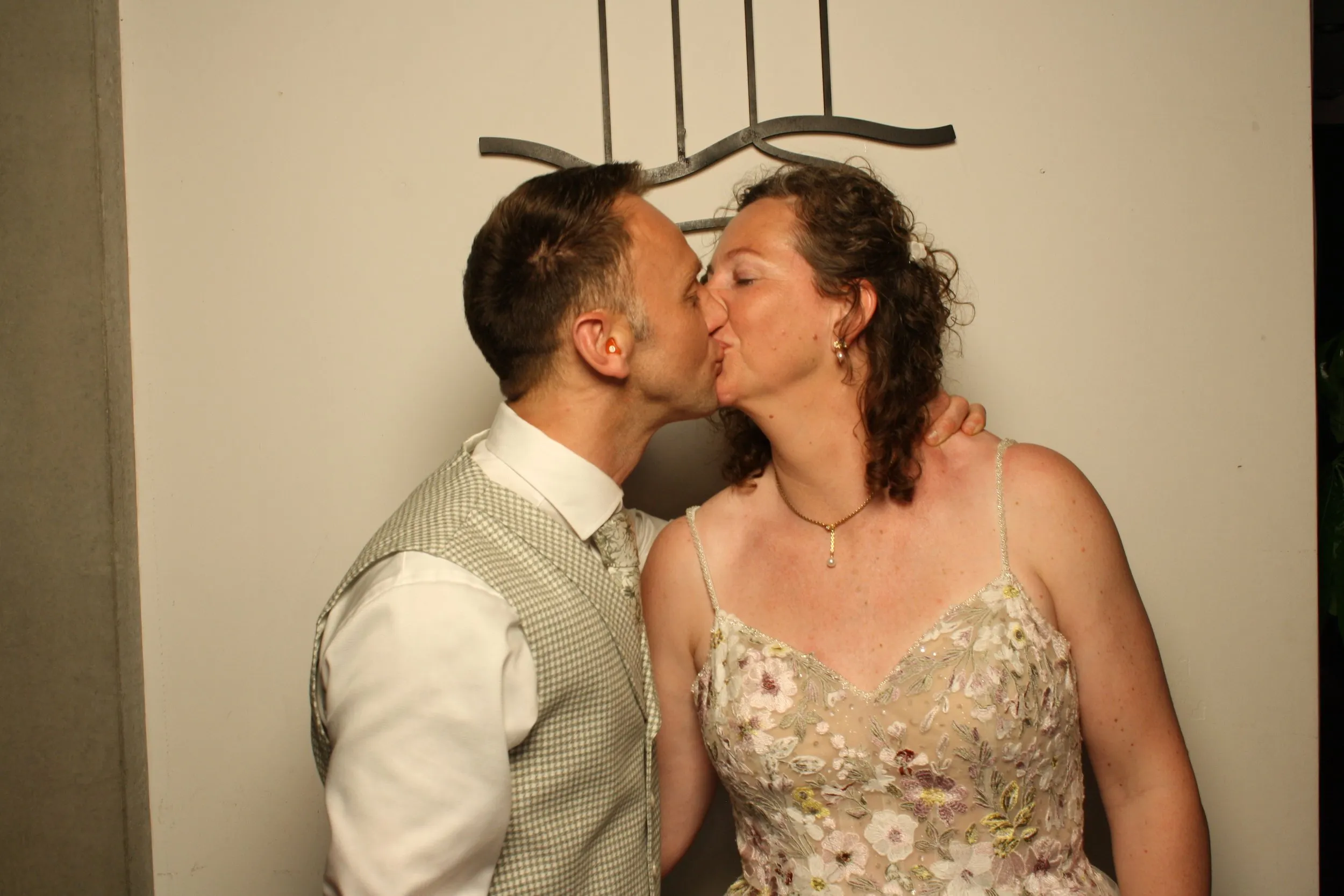 Een bruidspaar kust elkaar voor de camera van de photobooth